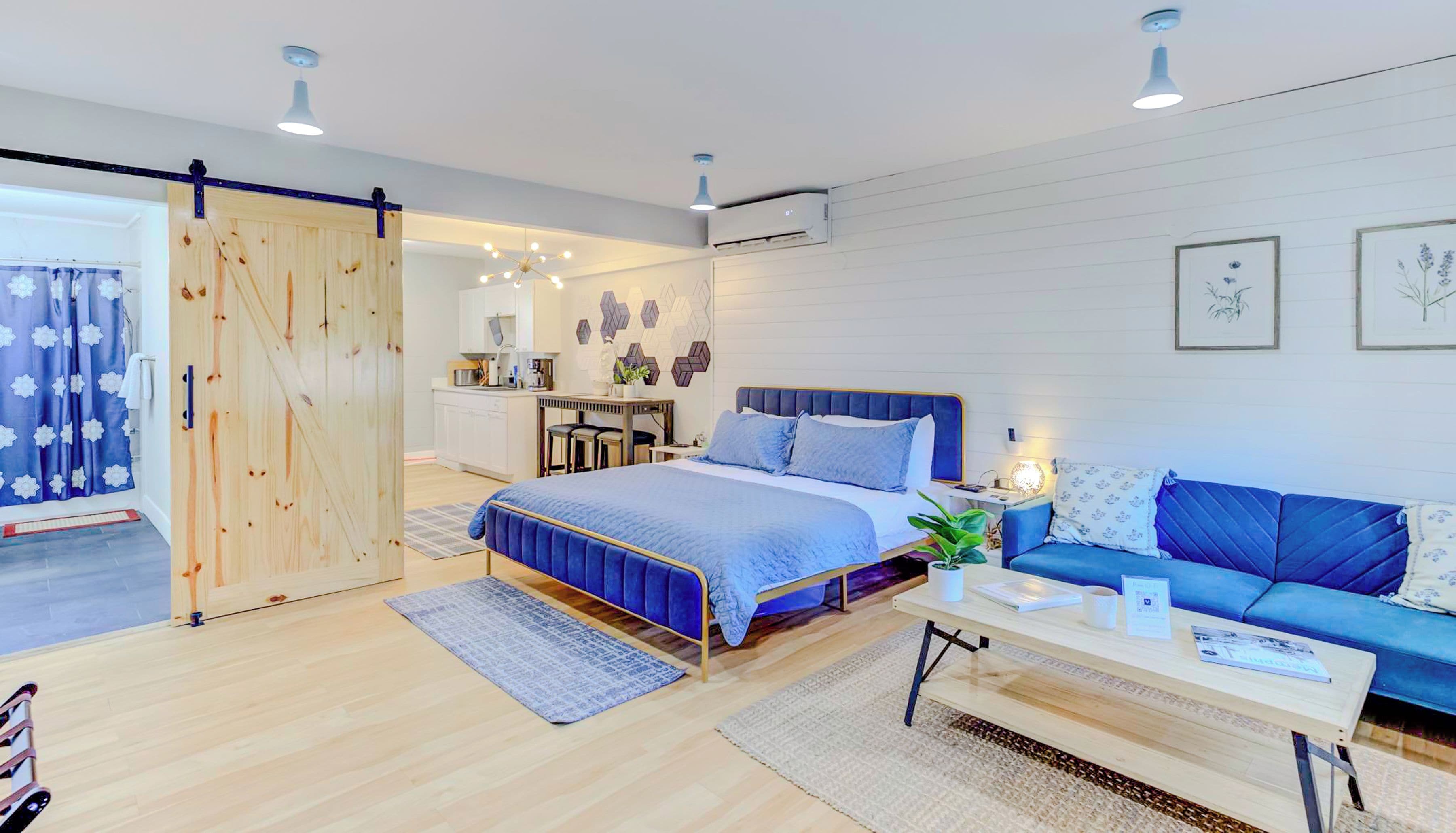 A modern bedroom with a bed, a blue sofa, a desk, and a sliding door.