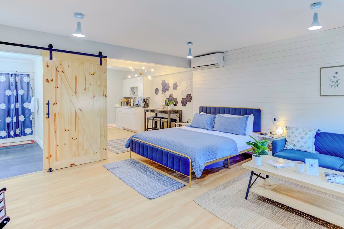 Un dormitorio moderno con cama, sofá azul, escritorio y puerta corredera.