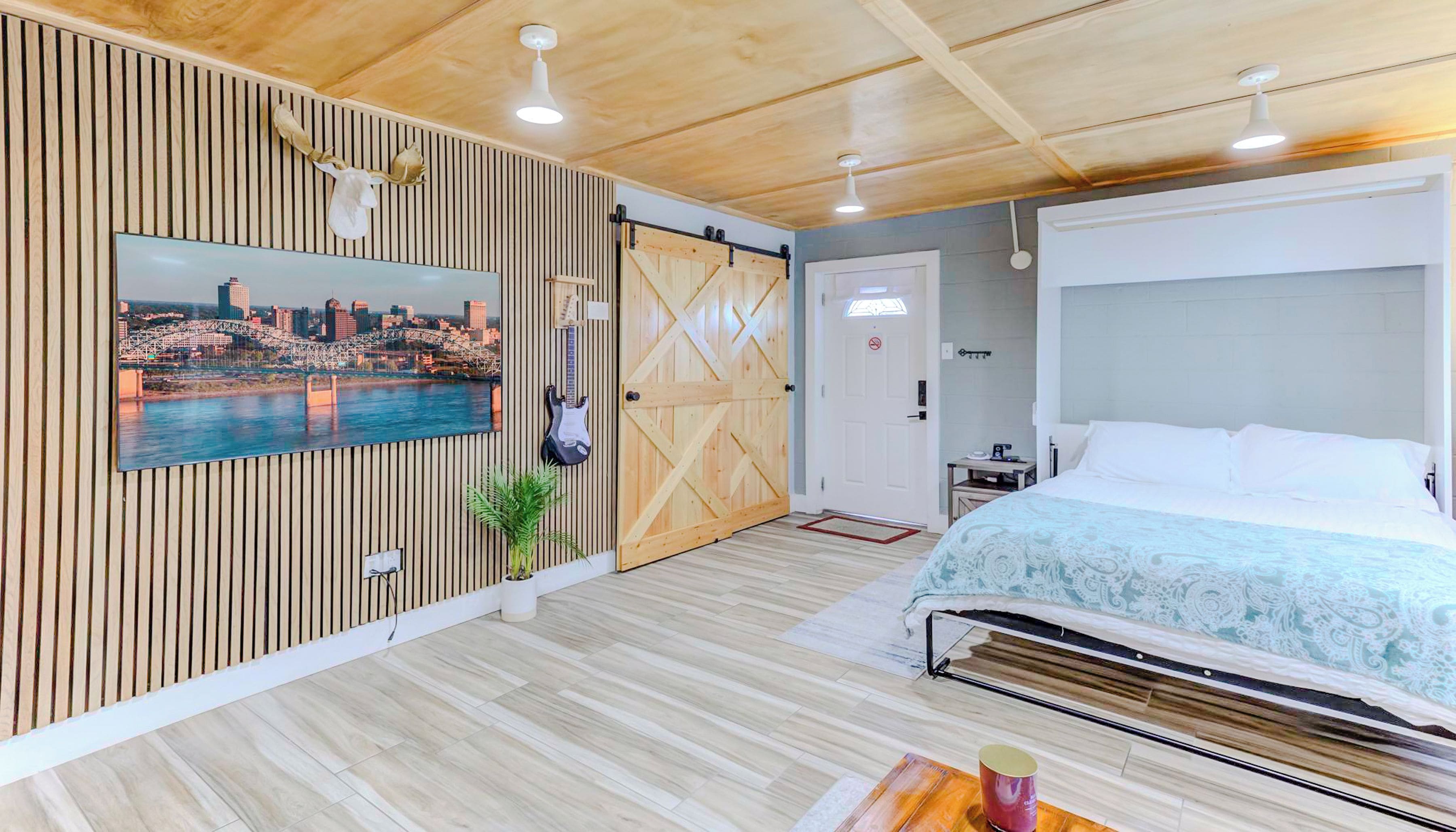 A hotel room with a cityscape view, a bed with a canopy, a guitar, and a wooden wall panel.