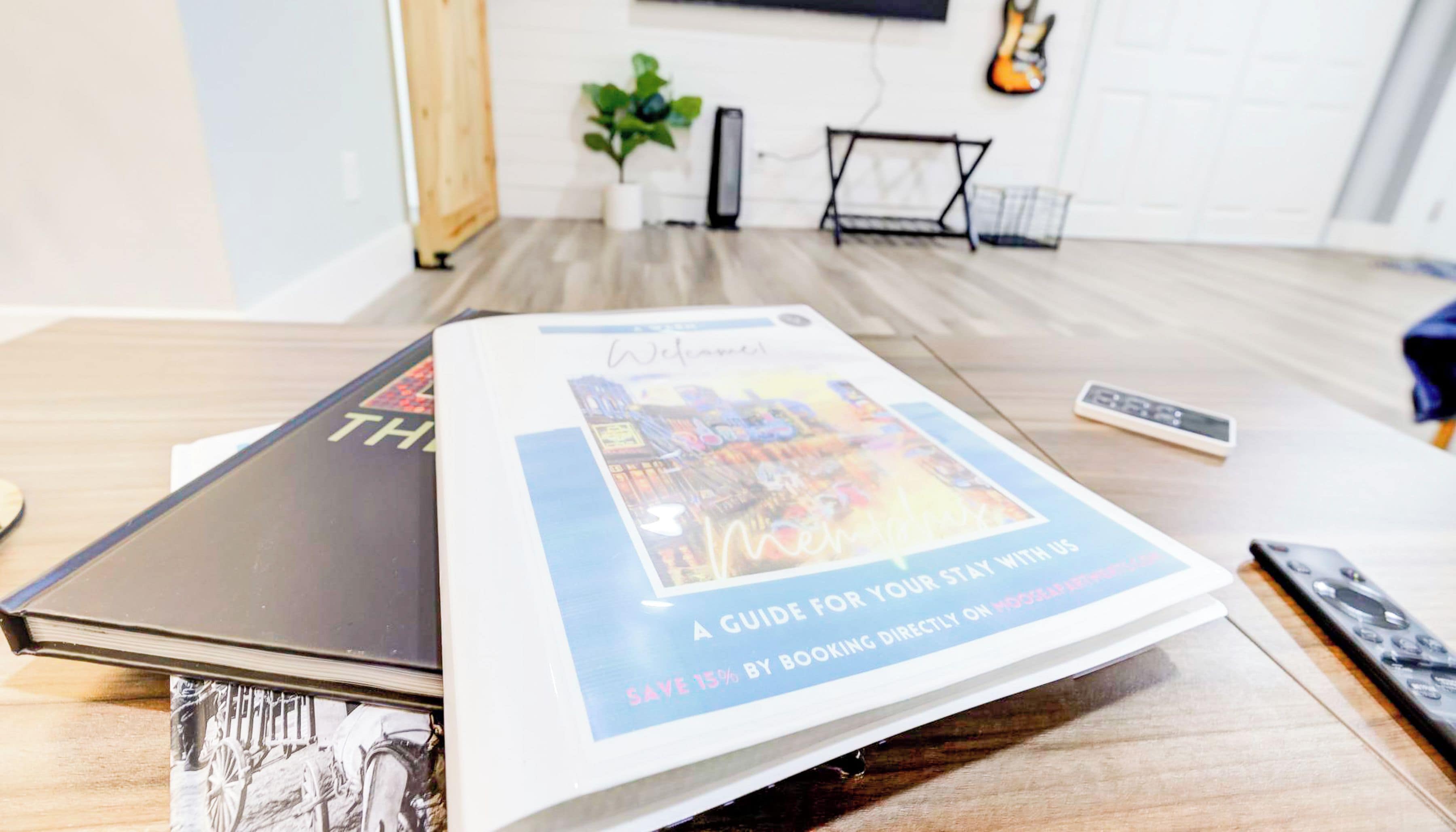 Ein Buch mit dem Titel „The Moose @ Memphis“ auf einem Tisch in einem Zimmer mit Fernseher, Gitarre und Pflanze.