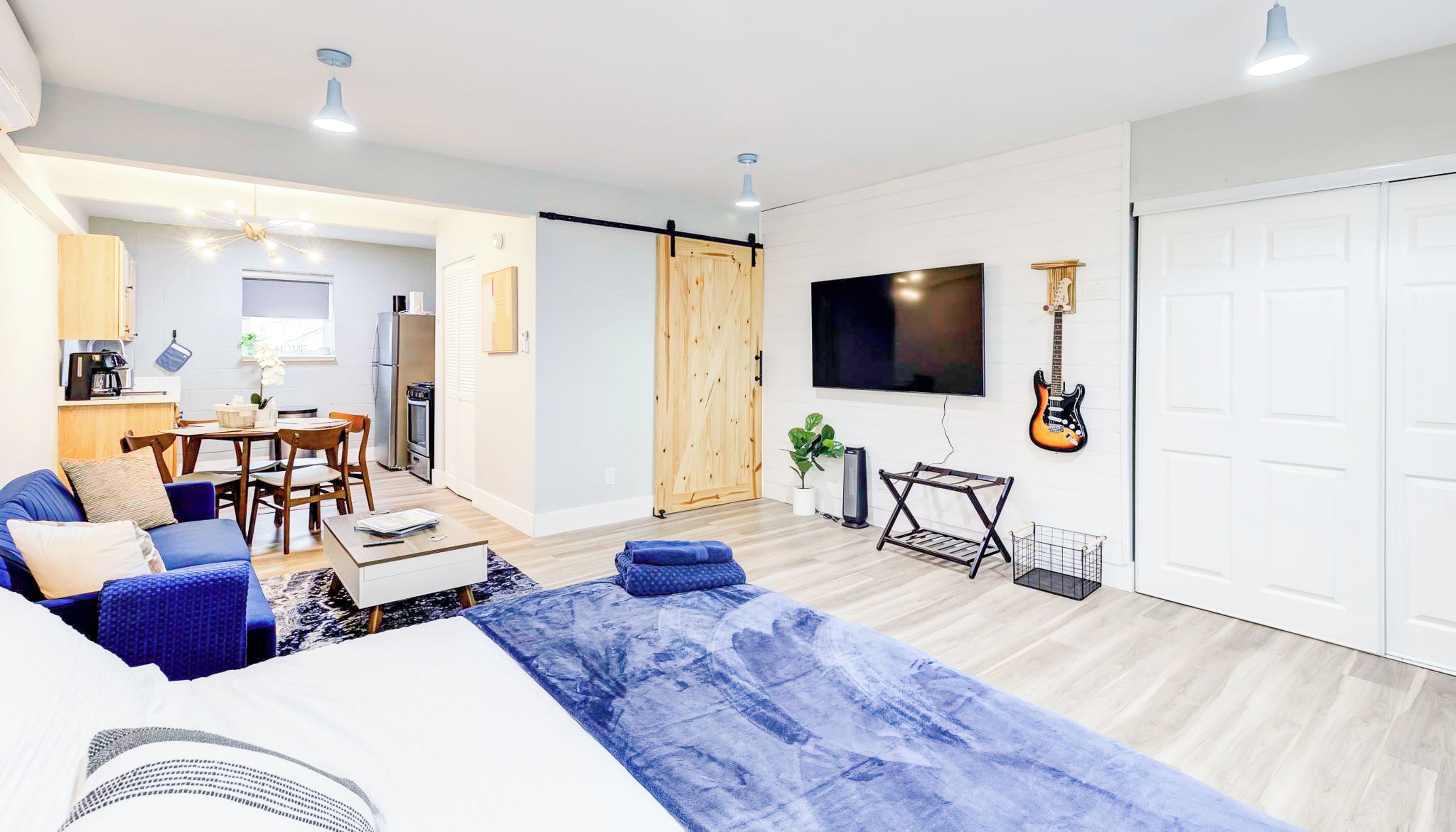 Een moderne woonkamer met een bank, salontafel en een aan de muur bevestigde televisie.