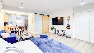Een moderne woonkamer met een bank, salontafel en een aan de muur bevestigde televisie.