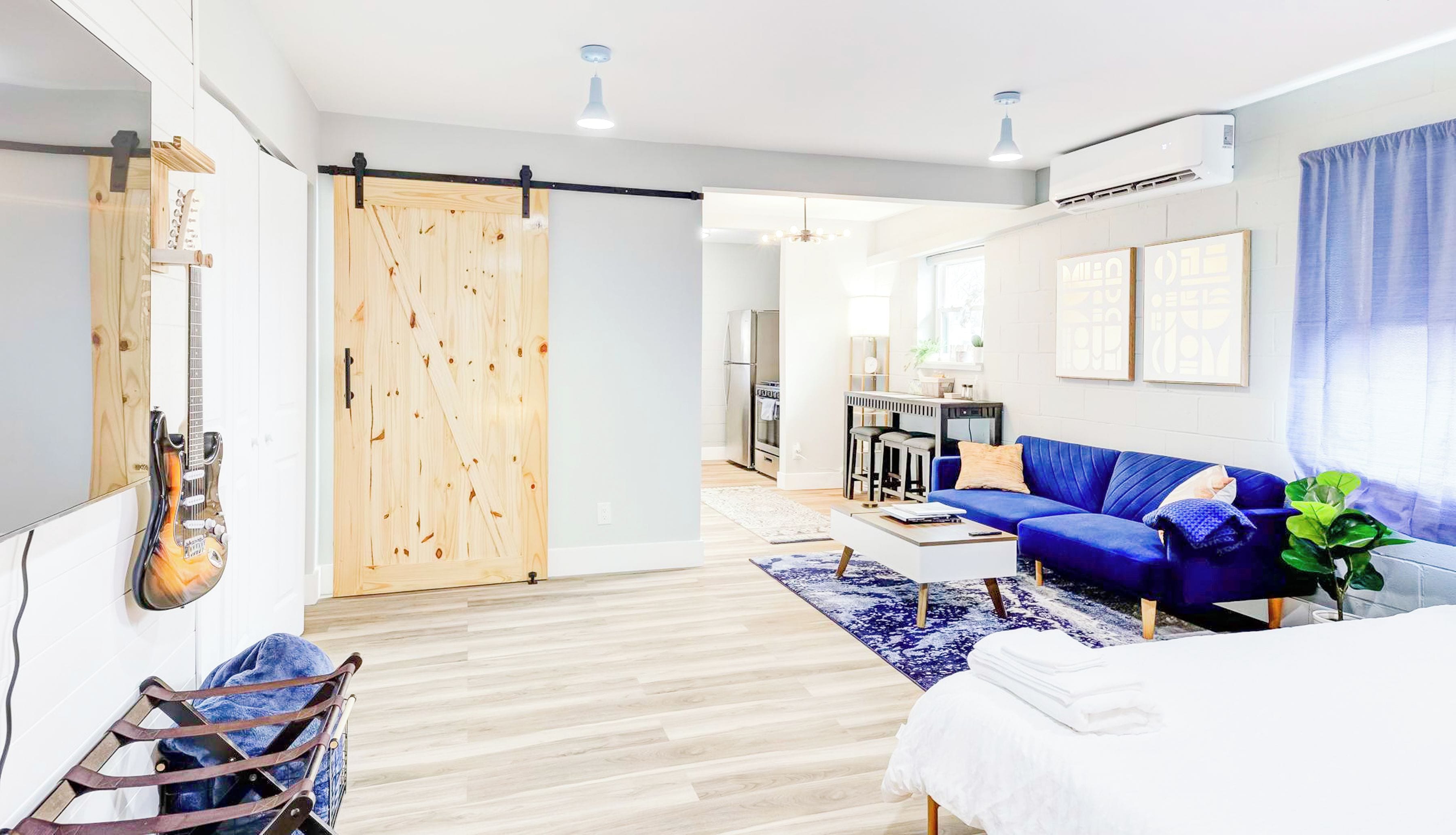 A modern living room with a blue sofa, a wooden sliding door, and a guitar on the wall.