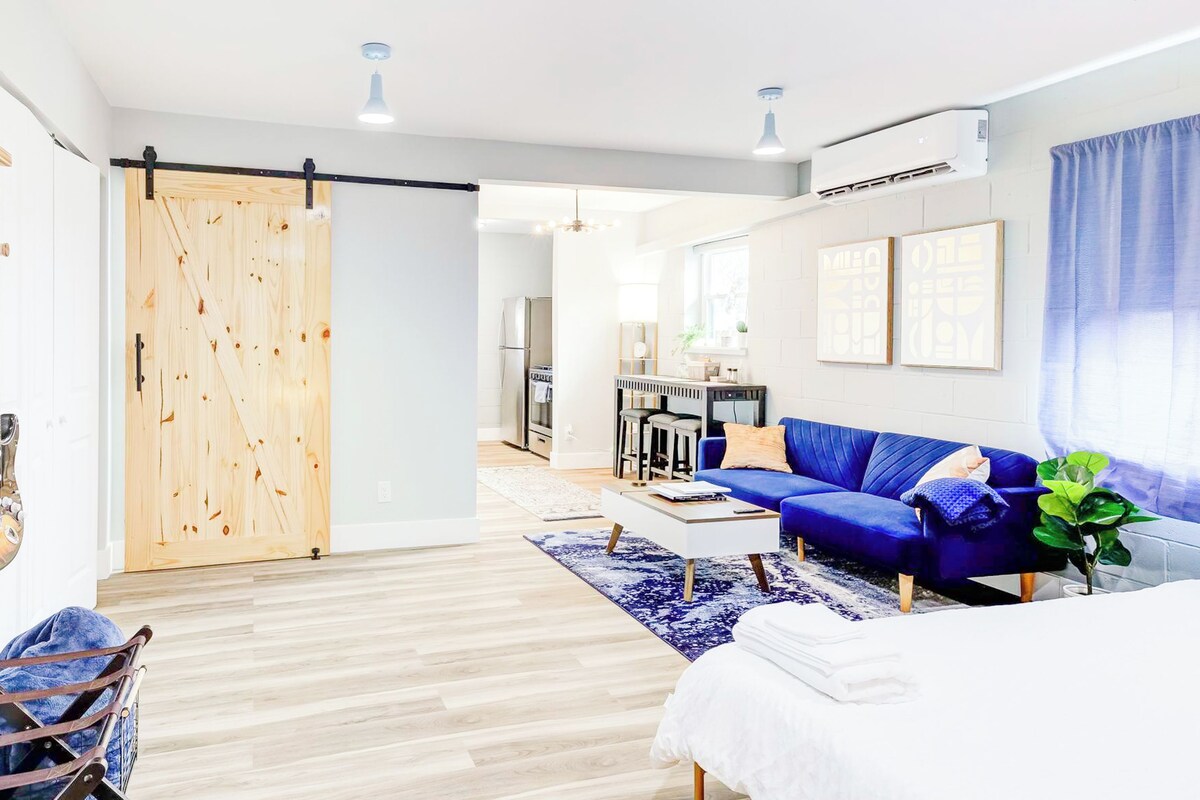 Una sala moderna con un sofá azul, una puerta corredera de madera y una guitarra en la pared.