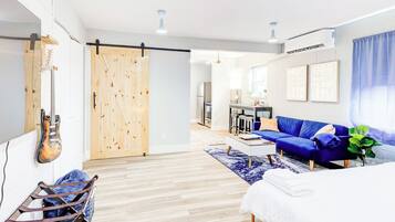 A modern living room with a blue sofa, a wooden sliding door, and a guitar on the wall.