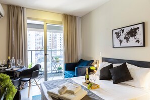 Ein Hotelzimmer mit Bett, einem Esstisch mit Stühlen, einem Balkon mit Vorhängen und einer Weltkarte an der Wand.