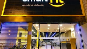 A modern building with a 'smart fit' sign, featuring a glass entrance and visible interior lighting. - Allianz parque AC Solário | Brazilian Corner. (São Paulo)
