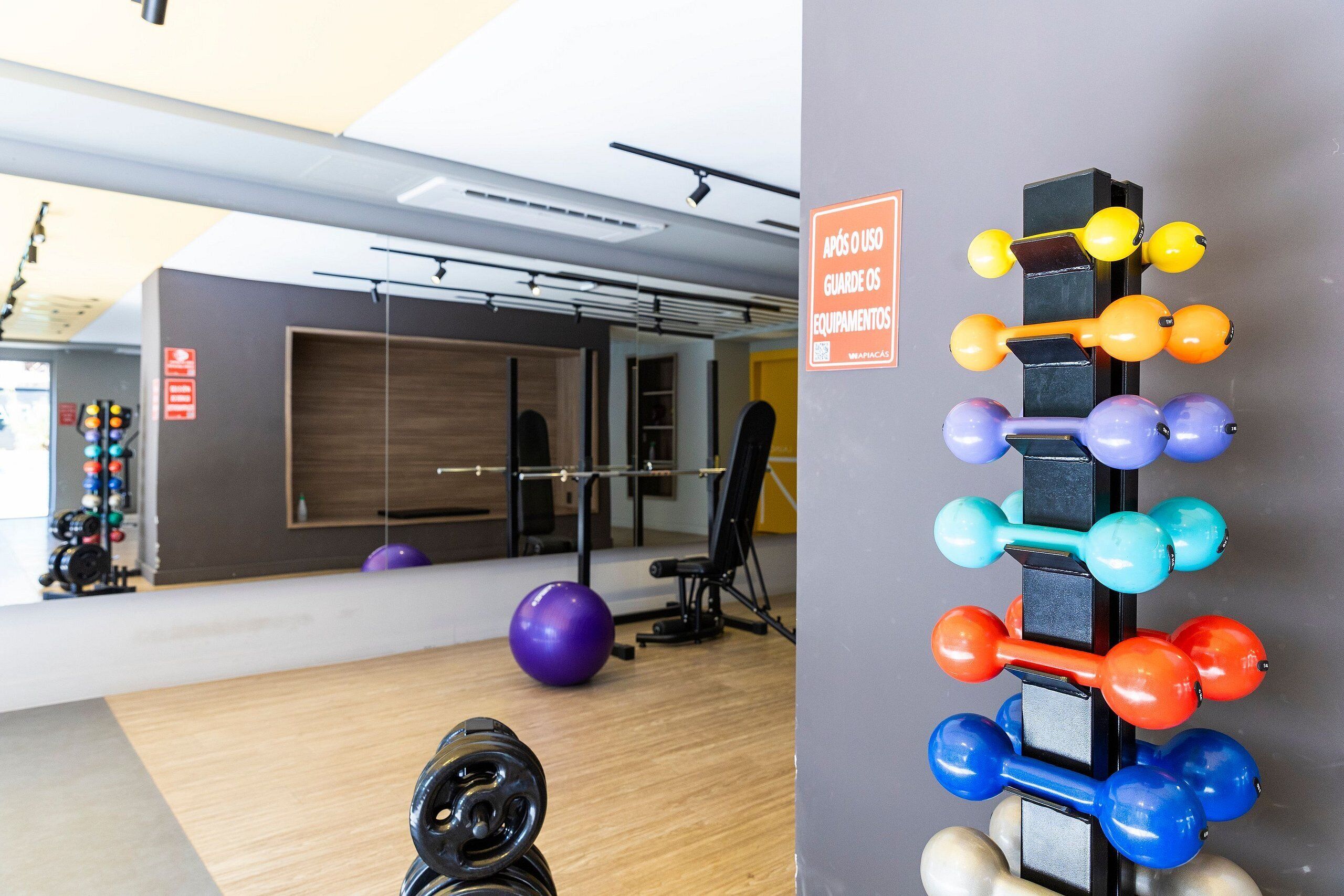 Un gimnasio con equipo de ejercicio, un espejo y un estante de mancuernas en la pared.