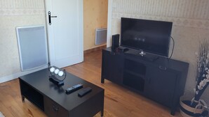 Una sala de estar con un mueble negro para entretenimiento, un televisor y un altavoz.