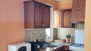 Una cocina compacta con armarios de madera, un refrigerador blanco, un microondas, una estufa a gas y un salpicadero de azulejos.