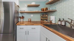 A kitchen with a stainless steel refrigerator, wooden countertops, white cabinets, and light blue tiled backsplash. - Heated Pool! Steps 2 beach! Luxurious King bed (Indian Rocks Beach)