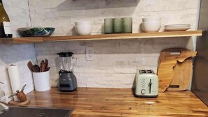 A kitchen with white cabinets, a wooden countertop, a toaster, a blender, and a wooden shelf above. - Coral Reef~90° Heated Pool~Remodeled~2 min 2 beach (Indian Rocks Beach)