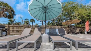 A poolside area with lounge chairs and umbrellas. - Coral Reef~90° Heated Pool~Remodeled~2 min 2 beach (Indian Rocks Beach)