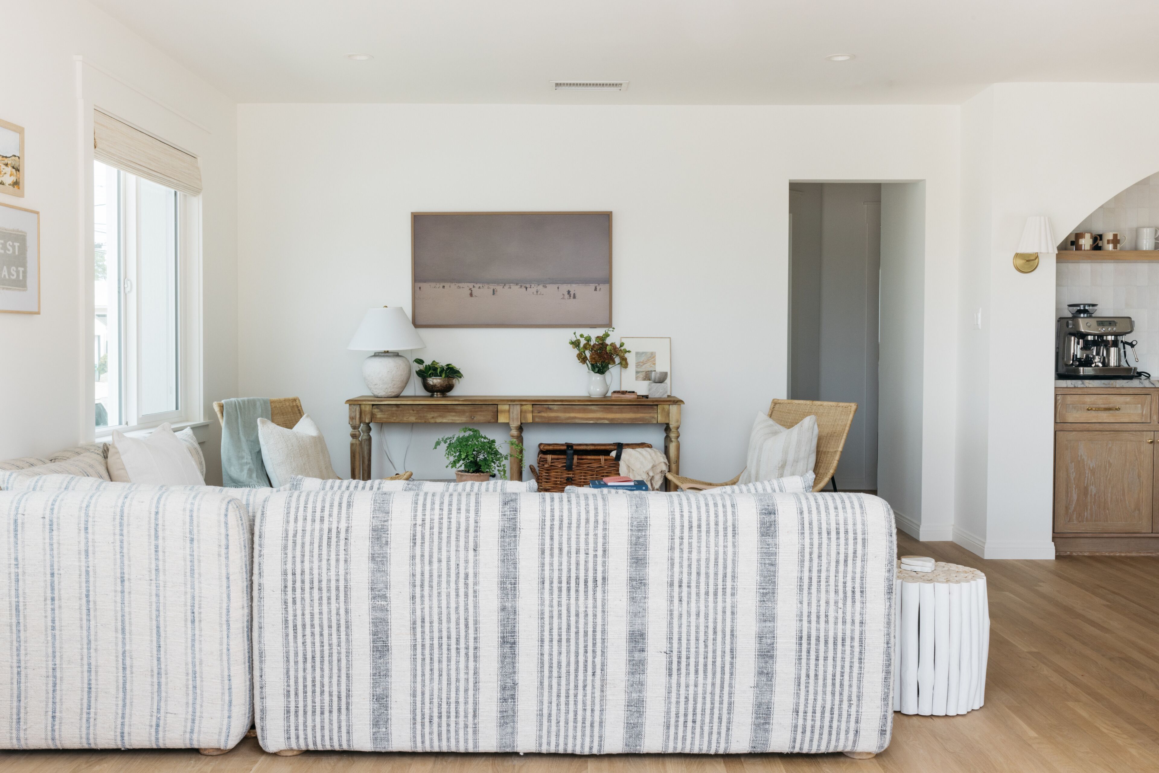 A modern living room with a striped sofa, a wooden coffee table, and a painting on the wall.