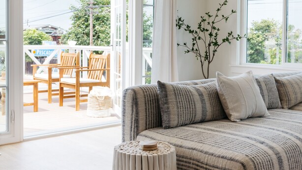 A modern living room with a sofa, a small round table, and a view of the outside. - New! Beautiful Beach House Steps from Sunset Cliffs!  (San Diego)