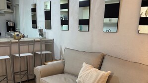 A living room with a beige sofa, a coffee table, and a kitchen area with a coffee machine. - Casa Caracol, Apartamento Totalmente Equipado Para su Estancia en San Carlos Son (San Carlos Guaymas)