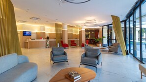 Eine moderne Lobby mit Empfangsschalter, Sitzgelegenheiten und großen Fenstern.