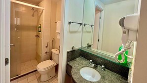 Ein Badezimmer mit Dusche, Toilette, Waschbecken und einem Fön auf der Ablagefläche.