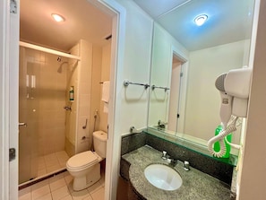 Ein Badezimmer mit Dusche, Toilette, Waschbecken und einem Fön auf der Ablagefläche.