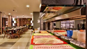 Ein reichhaltiges Buffet mit verschiedenen Speisen und eine Sitzgelegenheit mit Tischen und Stühlen.