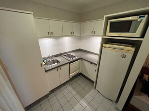 Una cocina compacta con lavamanos, estufa y microondas.