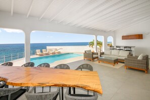 A spacious outdoor area with a pool, lounge chairs, and a wooden table.