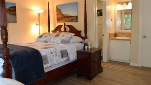 A bedroom with a four-poster bed, a nightstand, a dresser, a mirror, and a bathroom with a sink and mirror. - Single-level, fenced backyard, & quiet neighborhood (Beaverton)