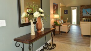 A living room with a wooden console table, a large mirror, and a fireplace. - Single-level, fenced backyard, & quiet neighborhood (Beaverton)