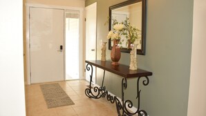 A hallway with a wooden console table, a mirror, and a vase with flowers. - Single-level, fenced backyard, & quiet neighborhood (Beaverton)