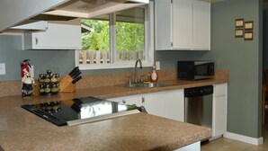 A kitchen with a granite countertop, white cabinets, a stainless steel sink, a microwave, and a dishwasher. - Single-level, fenced backyard, & quiet neighborhood (Beaverton)