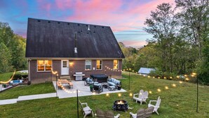A house with a brick exterior, a large deck, outdoor seating, and a fire pit.