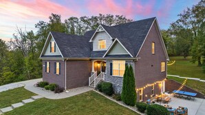 A two-story house with a brick exterior, a front porch, and a patio with outdoor furniture.