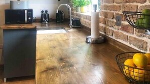 Una cocina con mostrador de madera, un lavamanos, un microondas y una pared de ladrillo.