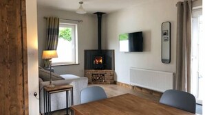 Una sala de estar acogedora con chimenea, una mesa de comedor y un televisor montado en la pared.