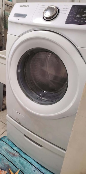 Vue de face d’un lave-linge à chargement frontal de la marque Samsung, doté d’un panneau de commande, d’une grande porte transparente et d’un autre panneau de commande avec divers réglages.