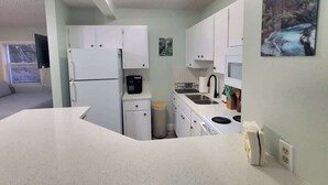 A compact kitchen with white cabinets, a refrigerator, a sink, and a stove. - NEW! Ocean Breeze! 10 Steps 2 beach! Beach view! (Clearwater)