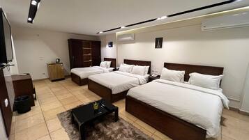 A hotel room with two beds, a small table, a wardrobe, and a TV.