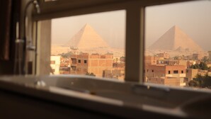 A view through a window of a building with two pyramids in the background. - King Khafren View INN (Giza)