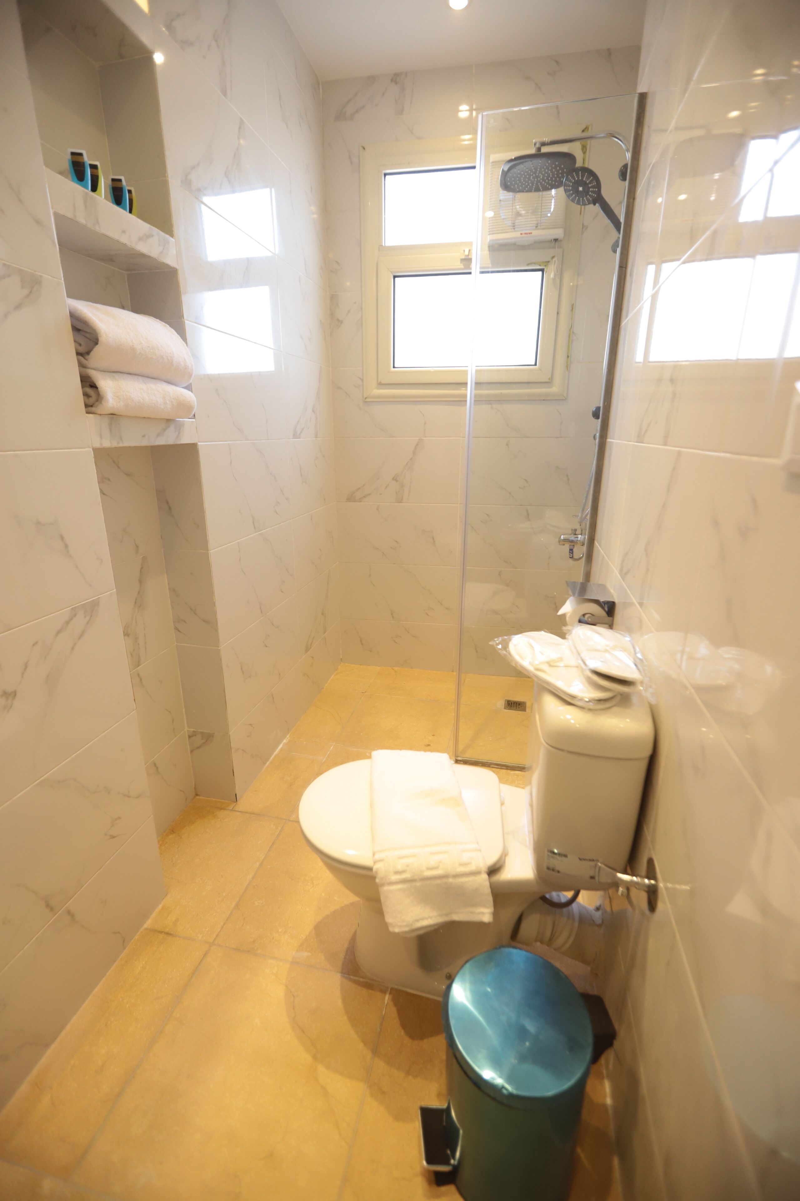 Een kleine badkamer met toilet, douche en een douchecabine met glazen wanden.