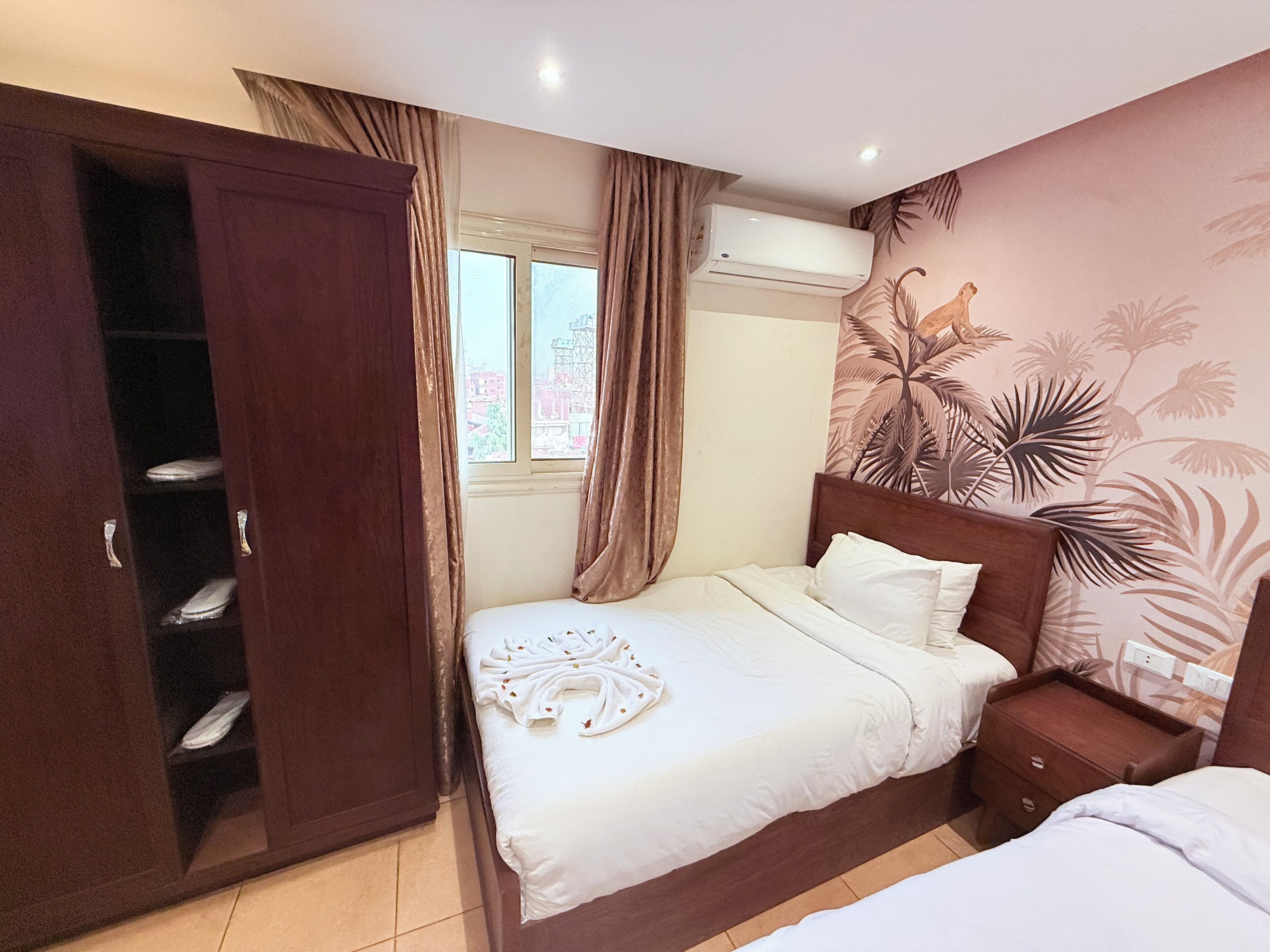 A bedroom with a bed, a wardrobe, a nightstand, and an air conditioning unit.