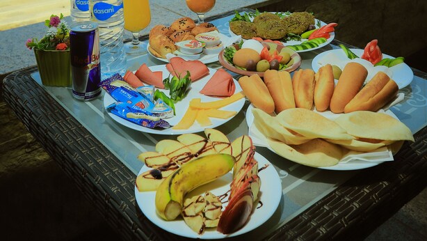 A table with food and drinks on a balcony overlooking pyramids. - King Khafren View INN (Giza)