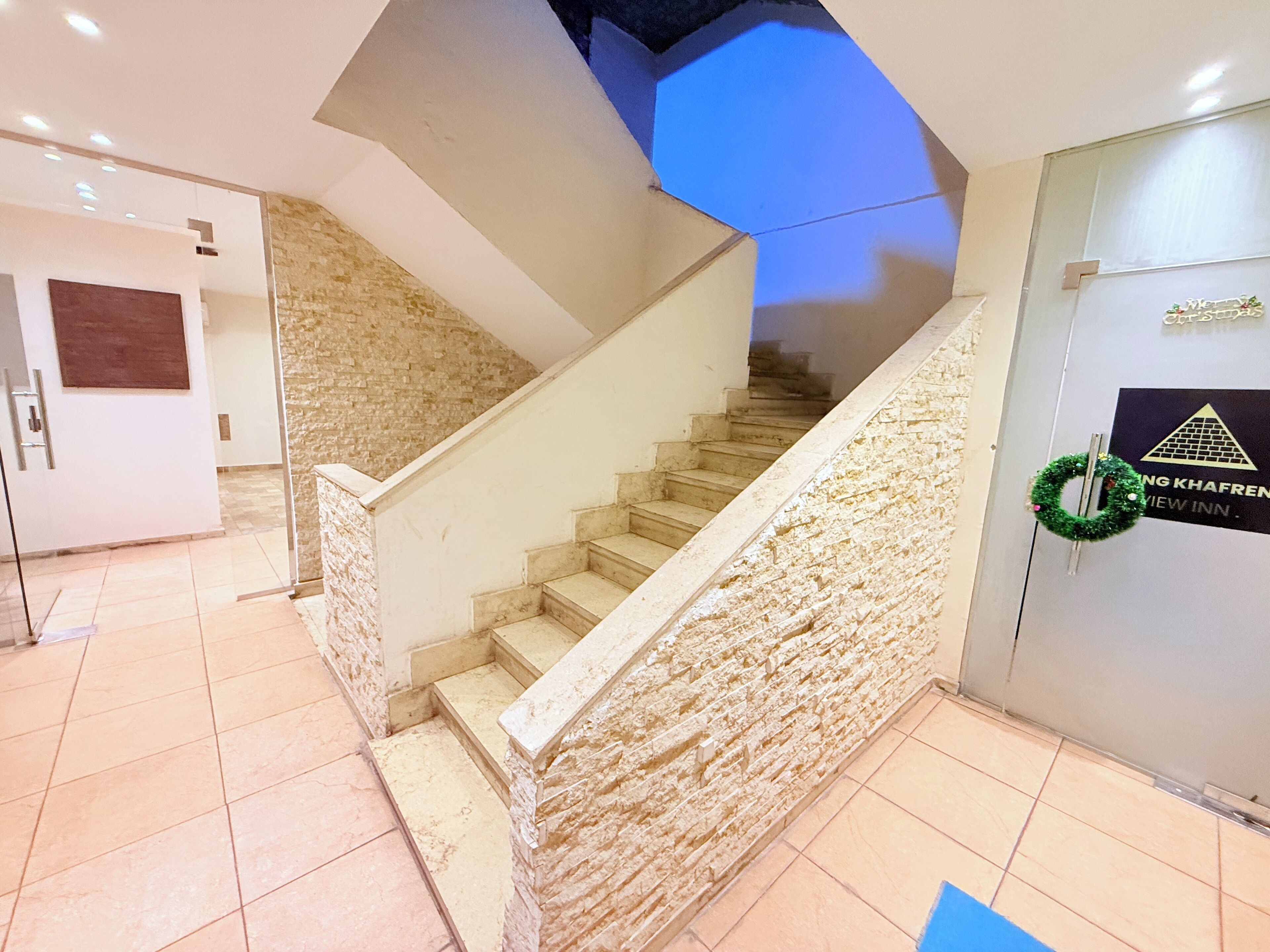 Una escalera con un muro de piedra a un lado y un vidrio a otro.