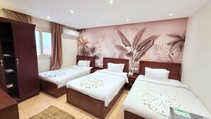 A hotel room with three beds, a wardrobe, a window with curtains, and a tropical-themed wall mural. - King Khafren View INN (Giza)