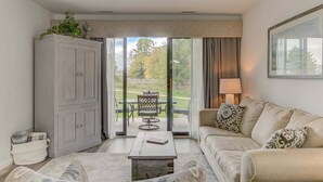 A living room with a sofa, a coffee table, a cabinet, and a view of a patio with outdoor furniture. - The Shores Beach Front Condo Unit 5593 (Williamsburg)
