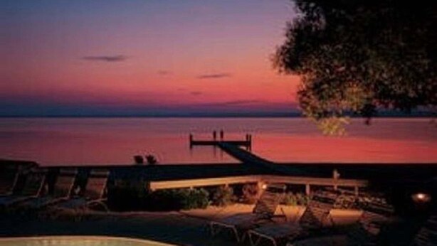 A pool area with lounge chairs and a view of the sea at sunset. - The Shores Beach Front Condo Unit 5593 (Williamsburg)