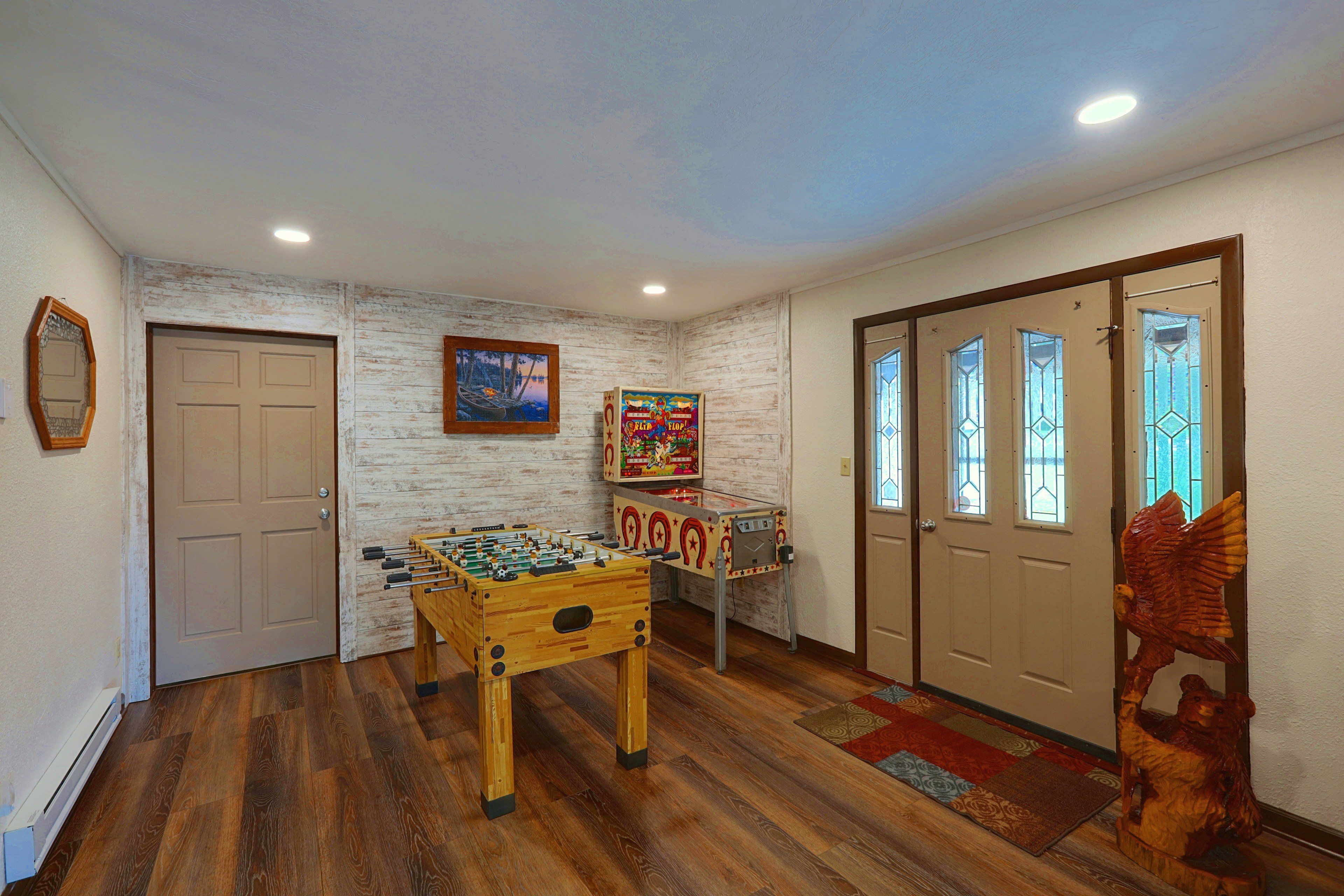 A room with a foosball table, a wooden door, a mirror, and a window with a view.