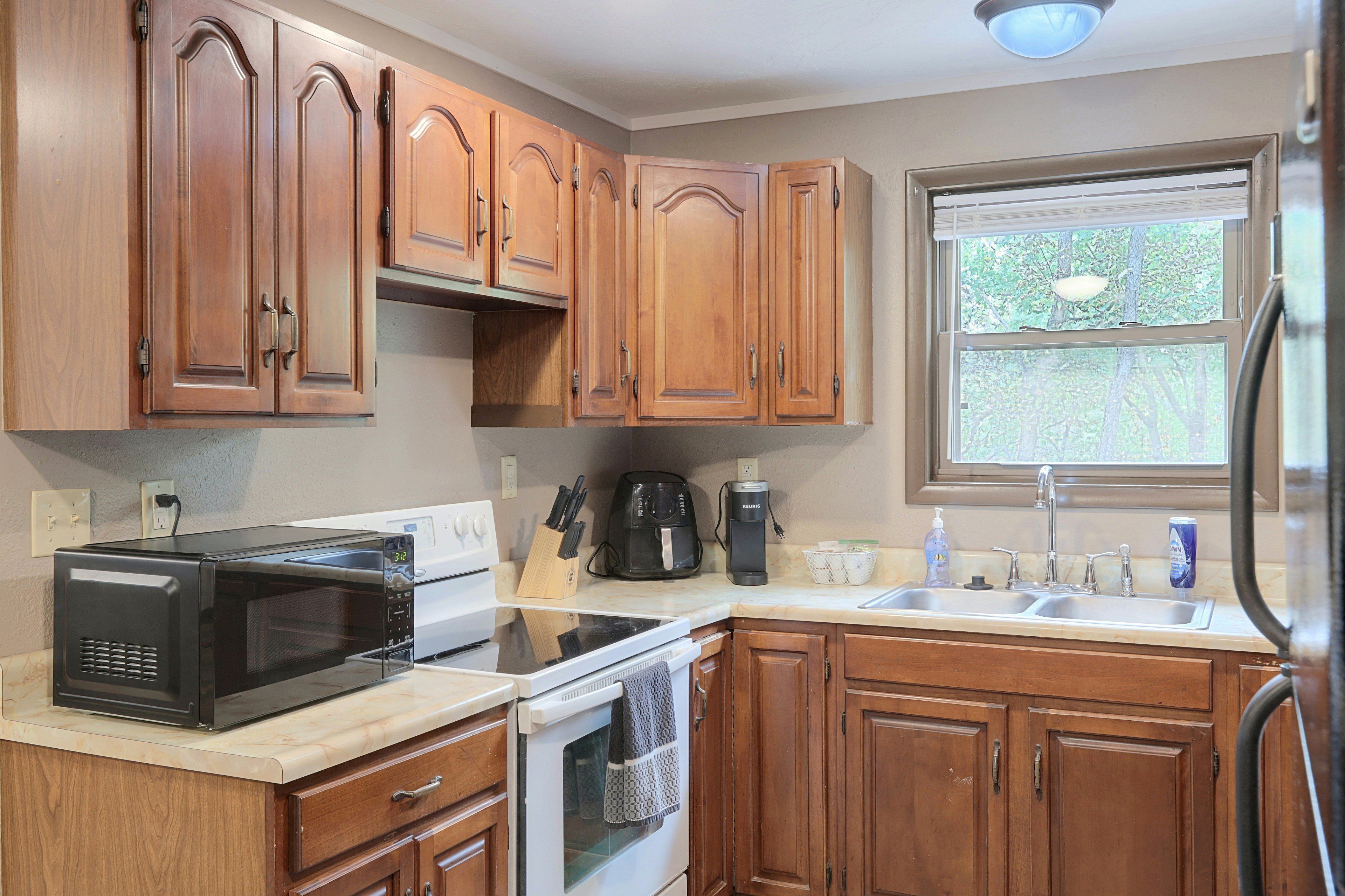 A kitchen with wooden cabinets, a microwave, an oven, a coffee maker, and a sink.