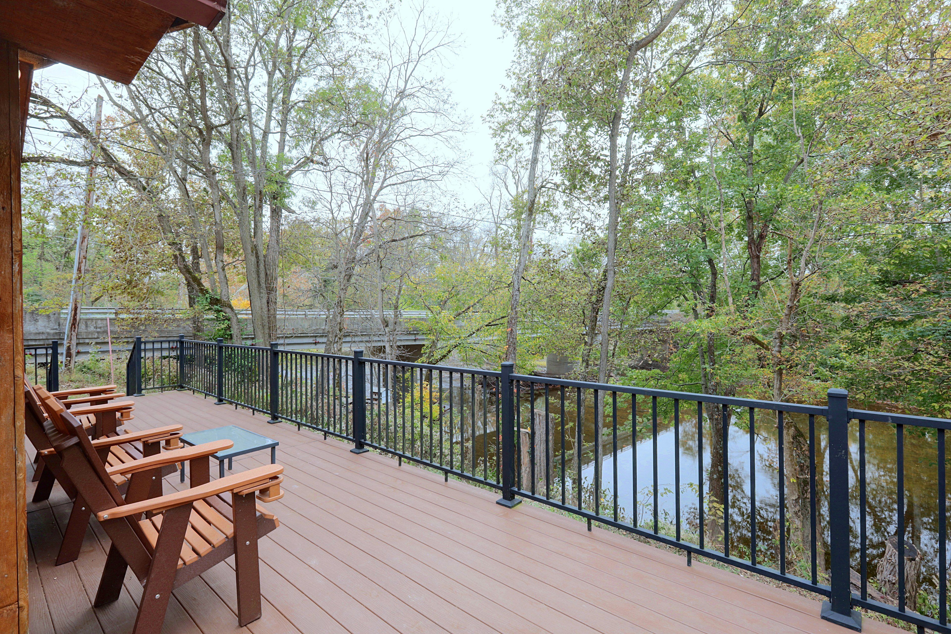 A wooden deck with picnic tables overlooking a body of water and trees.