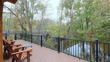 A wooden deck with picnic tables overlooking a body of water and trees.