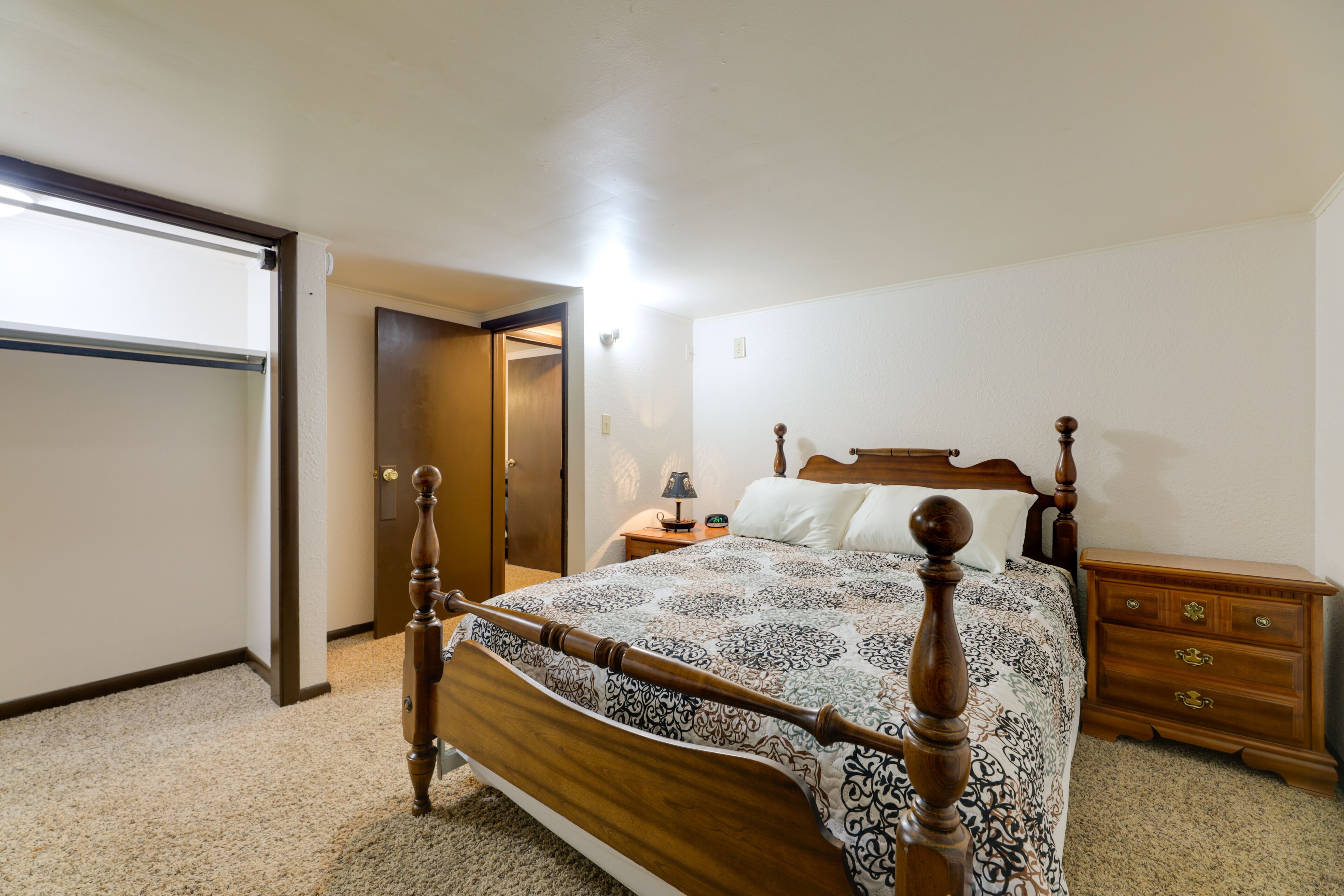 A bedroom with a wooden bed, a nightstand, a dresser, and a closet.